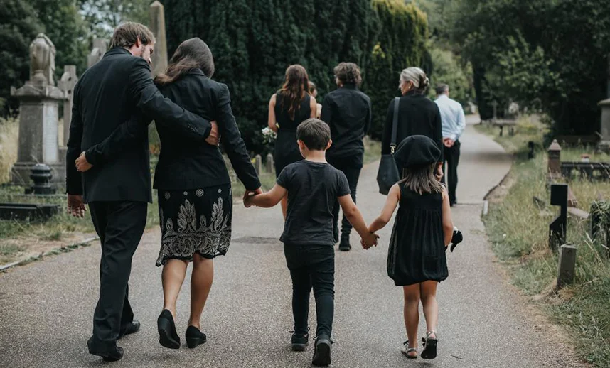 Family walking together through a cemetery, holding hands, on the way to a funeral service