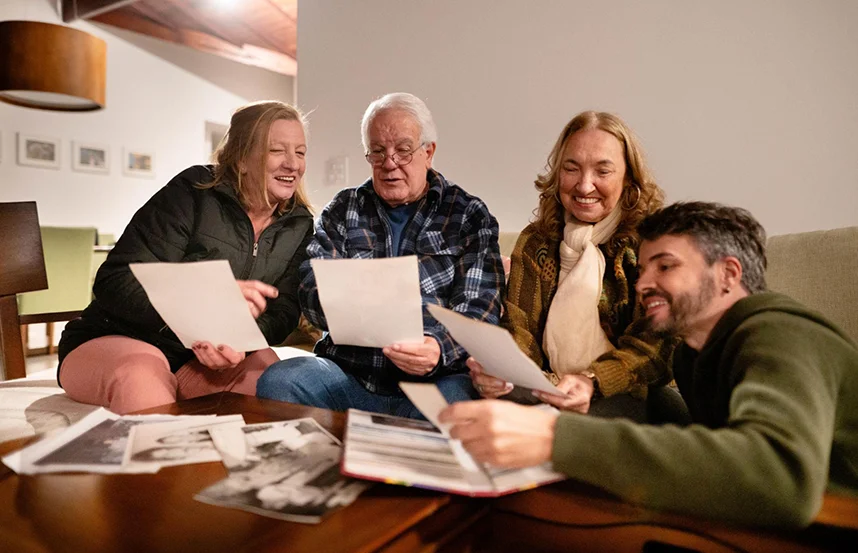 Family sitting together on a sofa, looking through old photographs and sharing memories