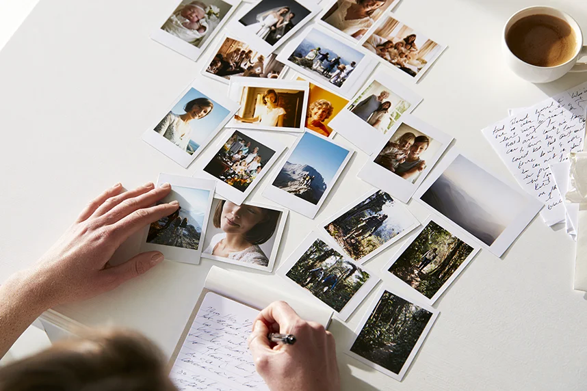 Hand-written notes and photographs laid out on a table while writing a funeral eulogy